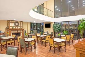 a restaurant with tables and chairs and a fireplace at Baymont by Wyndham Louisville Airport South in Louisville