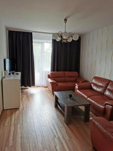 ein Wohnzimmer mit braunen Ledersofas und einem Couchtisch in der Unterkunft Laisvės 10 in Telšiai