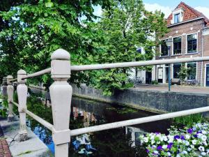 a fence next to a canal with flowers at Bed in de binnenstad ♡ bed downtown in Leeuwarden