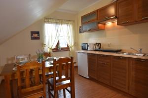 a kitchen with wooden cabinets and a table and chairs at Apartamenty przy basenie blisko morza Brown in Puck