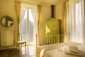 1 dormitorio con cama, ventana y silla en B&B Villa le Ortensie en Faggeto Lario 