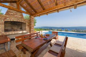 un patio con mesa de madera y chimenea en Lola - privacy, pool & view, en Kaštela
