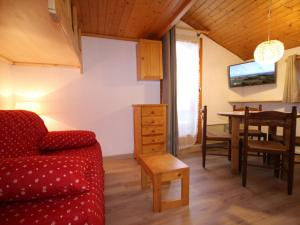 ein Wohnzimmer mit einem roten Sofa und einem Tisch in der Unterkunft Studio Les Saisies, 1 pièce, 2 personnes - FR-1-293-185 in Les Saisies