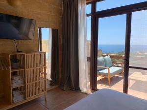 a bedroom with a bed and a tv and a balcony at 300y/o Farmhouse BLUE LAGOON VIEWS /AC/POOL QALA in Qala