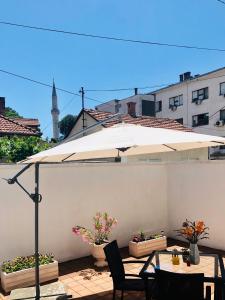 un patio con sombrilla, mesas y sillas en Dream Apartments, en Mostar