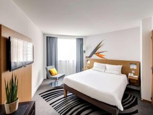 a hotel room with a bed and a tv at Novotel Paris Centre Gare Montparnasse in Paris