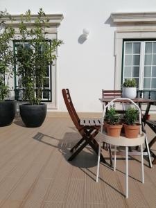 a patio with a table and chairs and potted plants at Hostel Rossio Alcobaça in Alcobaça