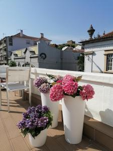 three white buckets filled with flowers on a balcony at Hostel Rossio Alcobaça in Alcobaça