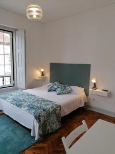 a bedroom with a large bed and two chairs at Hostel Rossio Alcobaça in Alcobaça