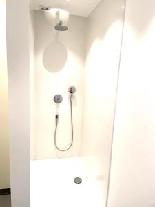 La salle de bains est pourvue d'une douche dans un mur blanc. dans l'établissement Chaff, à Ostende