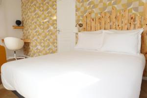 - une chambre avec un grand lit blanc et une tête de lit en bois dans l'établissement Villa Noellet - Clermont Ferrand, à Aubière