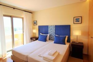 ein Schlafzimmer mit einem großen Bett mit blauen Kissen in der Unterkunft Anis Lux Tavira Residence Villa 5M in Luz de Tavira