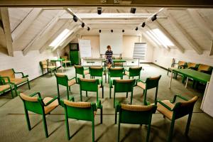 ein Zimmer mit grünen Stühlen und einer Person, die in einem Klassenzimmer steht in der Unterkunft Hotel Gasthof Lercher in Murau
