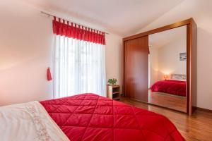 een slaapkamer met een rood bed en een spiegel bij Villa Mirela with a comfortable garden and pool in Grandići +34 foto's
