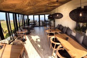 un restaurante con mesas y sillas de madera y ventanas en Hotel El Castillo de Los Locos, en Suances