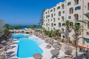 ośrodek z basenem, krzesłami i budynkiem w obiekcie Hotel Hopps w mieście Mazara del Vallo