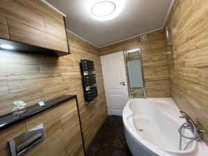 a bathroom with a large white tub and wooden walls at Apartament Martyna in Kłodzko