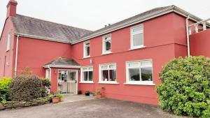 een rood huis met witte ramen bij Bridgeview Farmhouse Bed and Breakfast in Kilbrittain