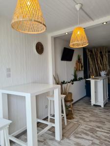 - une table et des chaises blanches dans une chambre avec deux lumières dans l'établissement Cap D'agde Naturiste Heliopolis 2 à 4 Personnes Appartement OSMOSE, au Cap d'Agde