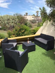 patio z 2 krzesłami i stołem na trawie w obiekcie Cap D'agde Naturiste Heliopolis 2 à 4 Personnes Appartement OSMOSE w Cap d'Agde