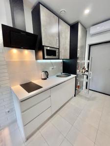 a white kitchen with a sink and a microwave at Апартаменты в Аркадии - Arcadia Sky Apartments in Odesa