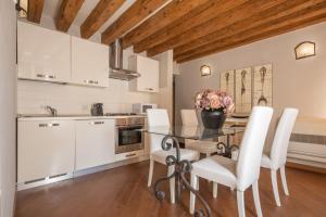 a kitchen with a glass table and white cabinets at Corte Contarina San Marco Apartment R&R in Venice