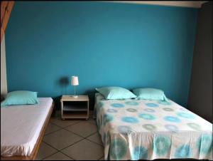 a room with two beds and a blue wall at Chez Sandrine in Cilaos