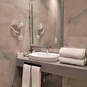 a bathroom with a sink and a mirror and towels at Iliad Hotel in Durrës