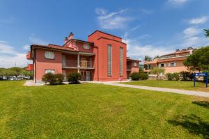 Un edificio rojo con un patio de césped delante. en Levant 200 in Marina Portoroz by Locap Group, en Portorož