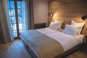 una camera da letto con un grande letto con lenzuola e cuscini bianchi di La Ferme a La Clusaz