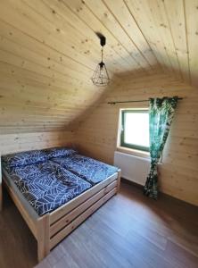 a bed in a wooden room with a window at Słoneczny Domek in Kluszkowce