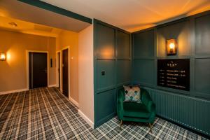 a hallway with a green chair in a room at Stay Hotel in Huddersfield