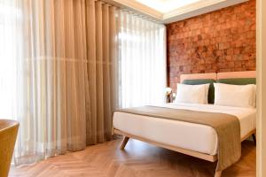 1 dormitorio con 1 cama con pared de ladrillo en My Story Hotel Tejo, en Lisboa