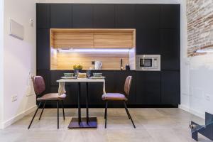 una cucina con armadi neri, tavolo e sedie di Amplísimo y coqueto apartamento de diseño en pleno centro a Siviglia