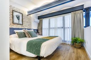 una camera con un grande letto e un muro di mattoni di Amplísimo y coqueto apartamento de diseño en pleno centro a Siviglia