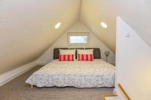 a attic bedroom with a bed with red pillows at Vila Renata Laure in Palanga