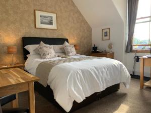 - une chambre dotée d'un grand lit avec des draps et des oreillers blancs dans l'établissement Morlea Bed & Breakfast, à Drumnadrochit