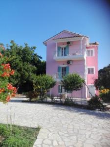 een roze gebouw met bomen ervoor bij Zeus and Hera Apartments in Nikiana