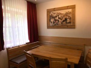 un comedor con una mesa de madera y una pintura en Familienappartements Eder en Kaprun