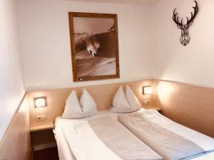 a bedroom with a white bed with a mirror and antlers at Familienappartements Eder in Kaprun