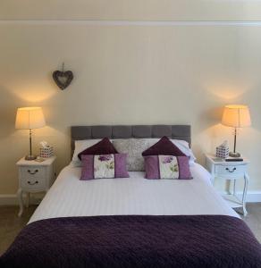 a bedroom with a large bed with purple pillows at Crown Hotel in Pateley Bridge