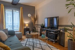 ein Wohnzimmer mit Sofa und Fernseher in der Unterkunft L'Arpege - appartement de charme cœur historique de Vannes in Vannes