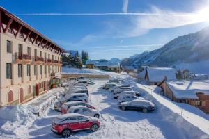 eine Reihe von Autos, die auf einem Parkplatz im Schnee geparkt sind in der Unterkunft VTF Le Grand Hotel in Montgenèvre