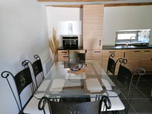 uma sala de jantar com uma mesa de vidro e cadeiras em Le moulin des vignes em Clairvaux-dʼAveyron