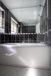 a bathroom with a tub and a large mirror at Finch House by RentMyHouse in Bullingham
