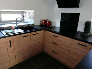 cocina con armarios de madera y encimera negra en Le moulin des vignes, en Clairvaux-dʼAveyron