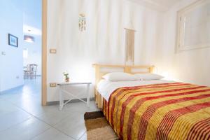 a bedroom with a bed with a striped blanket and a table at Tenuta Don Carmelo in Lecce +45 photos