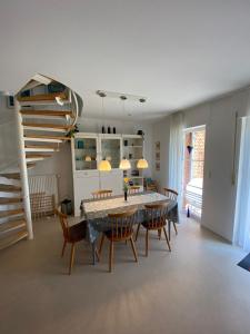 ein Esszimmer mit einem Tisch, Stühlen und einer Treppe in der Unterkunft Haus Windjammer in Friedrichskoog