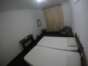 Habitación pequeña con 2 camas y silla en Hotel Cavalinho Branco, en Águas de Lindóia