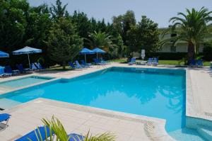 una gran piscina con sillas y sombrillas azules en Francisco Beach Hotel, en Agios Andreas - Mesenia